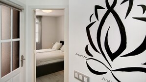 A room with a bed, a door, and a wall with a large black floral design. - Apartment "Casa Princesa" with Sea & Mountain View, Pool, Balcony & Wi-Fi (Playa del Cura)
