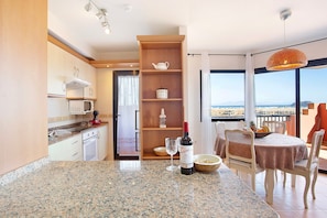 Eine moderne Küche mit Granit-Arbeitsplatten, einer Weinflasche und einem Essbereich mit Aussicht.