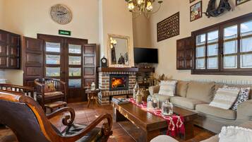 Una sala de estar acogedora con chimenea, muebles de madera, un sofá y un televisor.