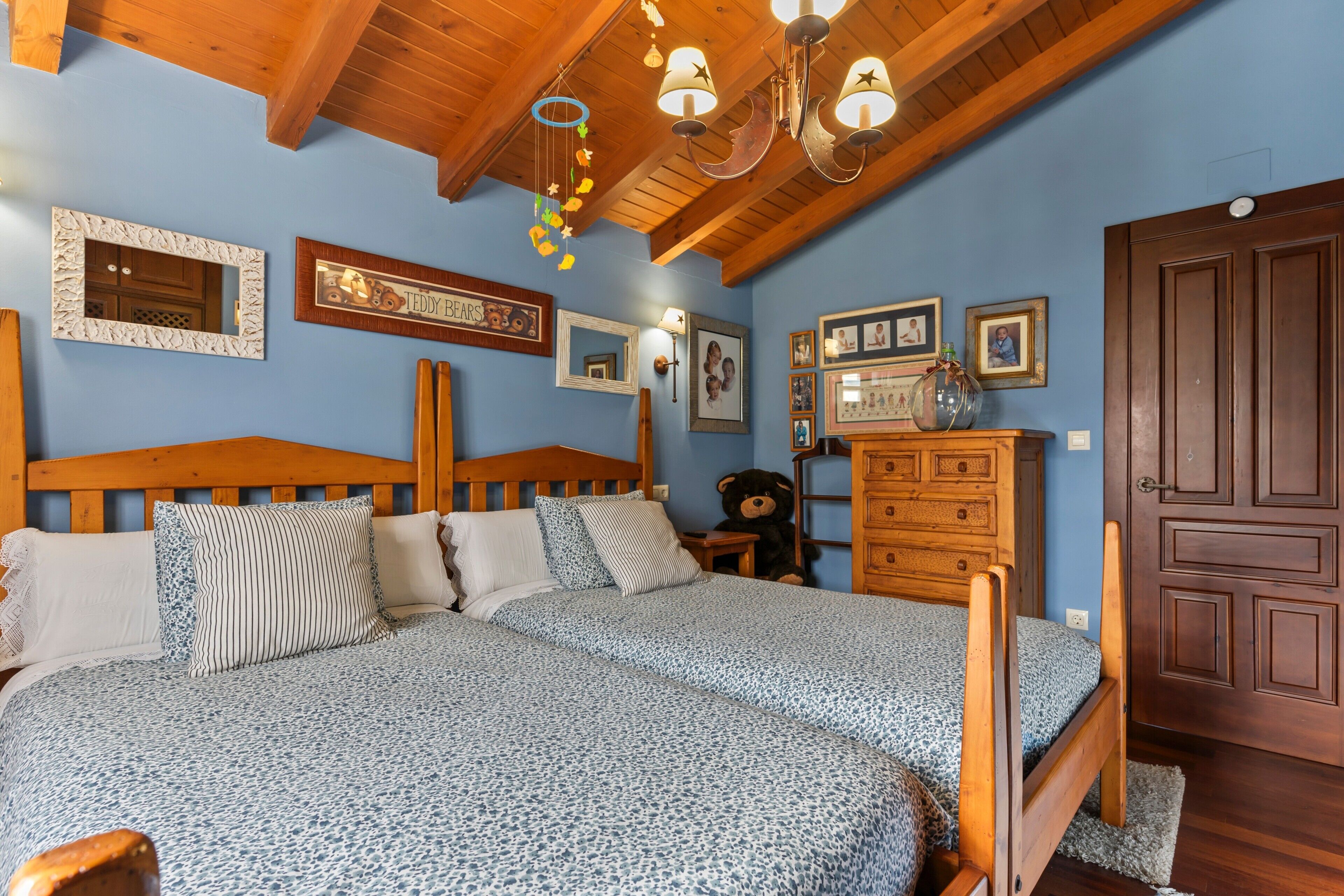 Un dormitorio con una cama de madera, un aparador y una araña.