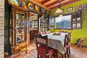 Un coin repas avec un buffet en bois, une table recouverte d’une nappe blanche et une vue sur l’extérieur.