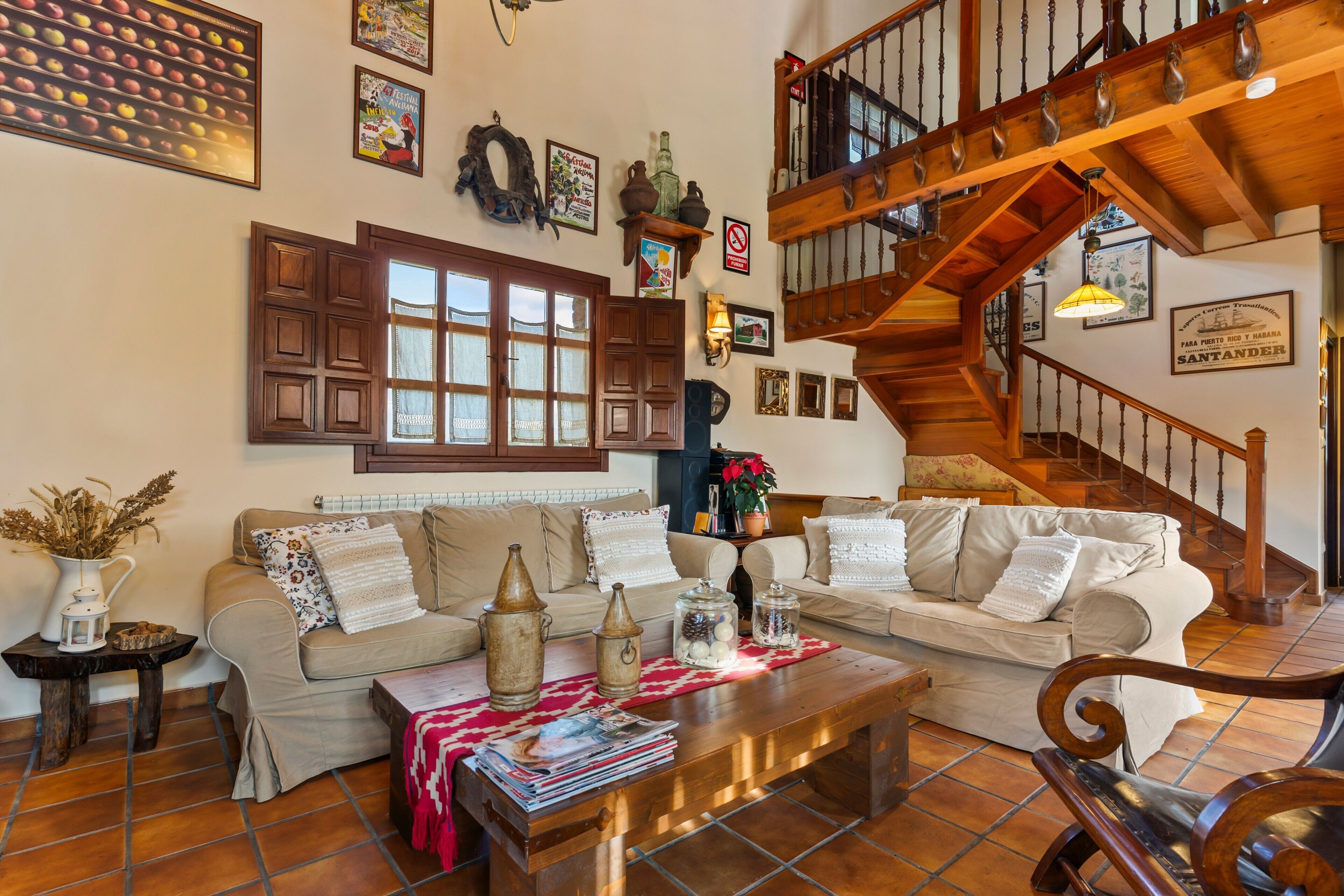 Un salon avec un escalier en bois, un ensemble de canapés et une table basse sur laquelle sont posés des magazines.