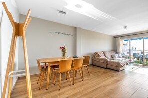 Een moderne woonkamer met een houten eettafel, een bank en een groot raam.