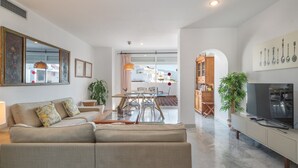 A modern living room with a sofa, TV, and dining area. - Spacious and Fantastic Views Apartment with Sea View, Pool, Garden & Wi-Fi (Nueva Andalucía)
