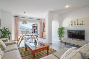 Ein modernes Wohnzimmer mit Sofa, Couchtisch, Fernseher und Essbereich.