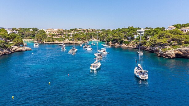 A marina with multiple sailboats docked, surrounded by rocky terrain and buildings. - Felipe 1-4 Apartment with Terrace, Shared Pool & Wi-Fi (Tourist Taxes Included) (cala dor)