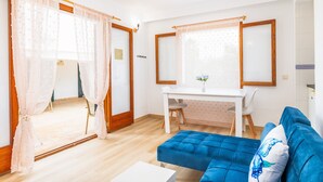 A room with a blue sofa, a white desk, and a dining table. - Felipe 1-4 Apartment with Terrace, Shared Pool & Wi-Fi (Tourist Taxes Included) (cala dor)