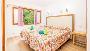 A bedroom with a bed, a window with curtains, a bedside table, and a nightstand. - Holiday Apartment "Felipe 2-2" with Terrace & Shared Pool (Tourist Taxes Included) (Cala Dor)