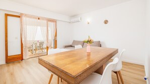 Un coin repas avec une table en bois, des chaises blanches, un vase de fleurs et un canapé.