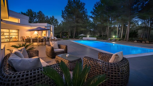 Ett modernt utomhusområde med pool, möbler i rotting och en matplats.