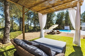 A covered outdoor seating area with a pool in the background. - Villa "Can Drago" Private Pool, Large Garden, Terrace, WiFi & A/C (ibiza)