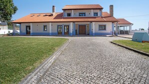 Una casa de dos pisos con techo de tejas, un porche delantero y un camino de entrada pavimentado.