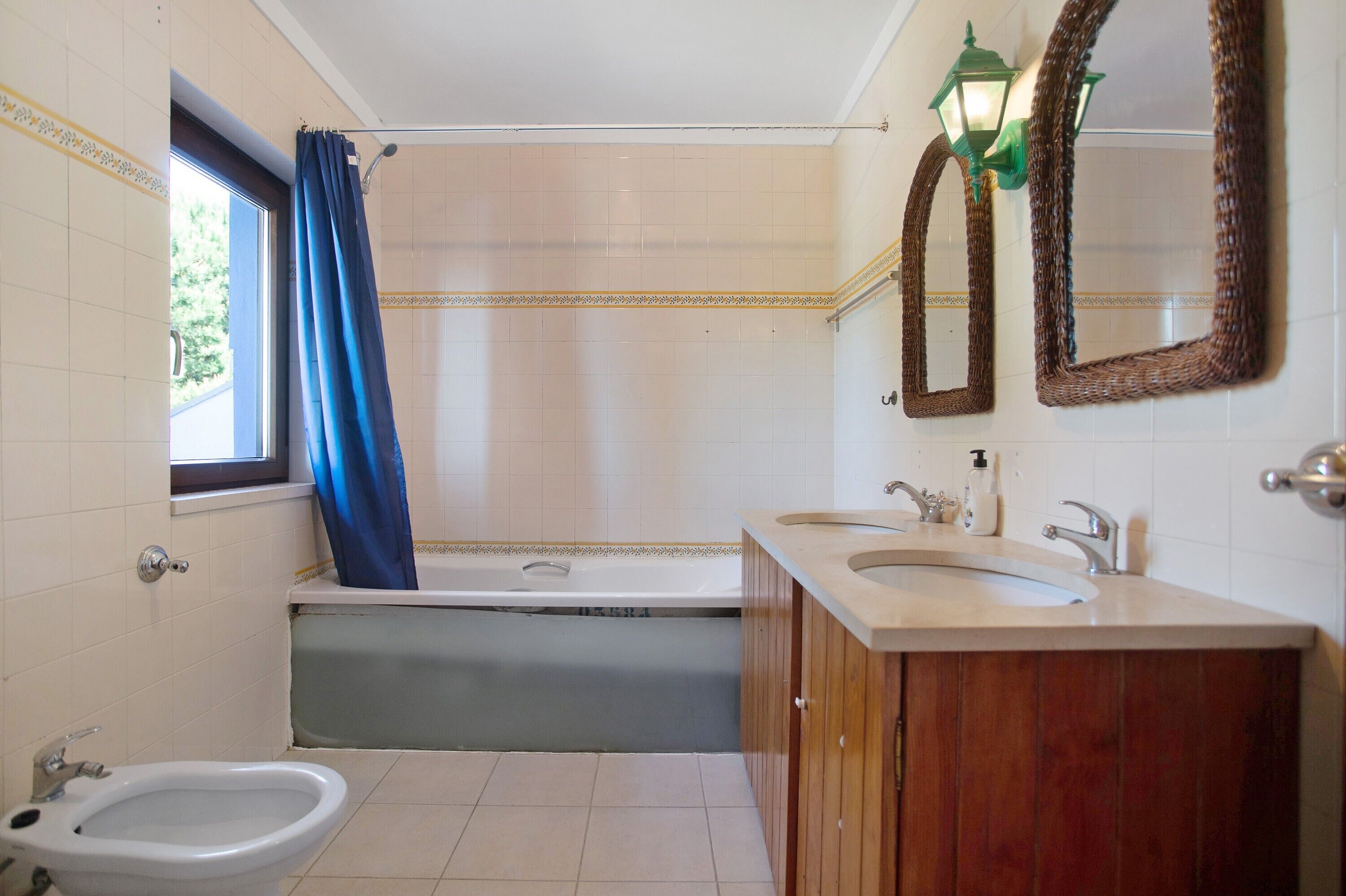 A bathroom with a bathtub, a bidet, a sink, and two mirrors.