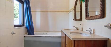 A bathroom with a bathtub, a bidet, a sink, and two mirrors.