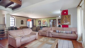 Un amplio salón con un gran sofá, una mesa de centro de vidrio y una chimenea.