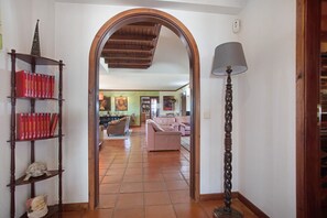 Une vue intérieure d’un salon avec un canapé, une lampe et une bibliothèque remplie de livres.