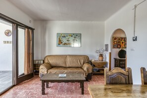 A living room with a sofa, coffee table, and a dining table.
