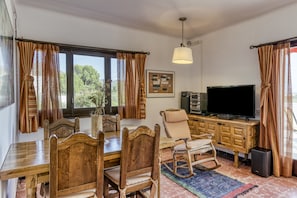A dining area with wooden furniture, a television, and a large window with curtains.