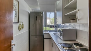 A compact kitchen with a refrigerator, stove, and microwave. - Penthouse with Sea Views in Roses, with Sea Views, Terrace and Wi-Fi (El Mas Boscà)