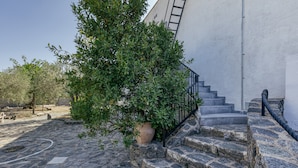 A stone staircase leading to a building with a metal railing, surrounded by greenery and a paved area. - Penthouse with Sea Views in Roses, with Sea Views, Terrace and Wi-Fi (El Mas Boscà)