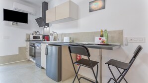 Een kleine keuken met een magnetron, koffiezetapparaat en een koelkast.