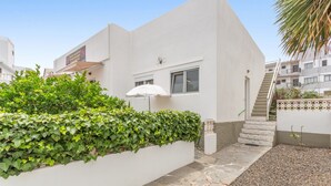 Ein modernes Gebäude mit weißer Fassade, einem Steinweg und einer weißen Mauer mit grünen Pflanzen.