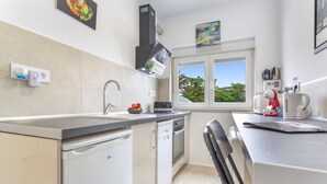 Eine moderne Küche mit Geschirrspüler, Backofen und einem Fenster mit Blick ins Grüne.