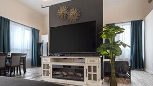 Ein modernes Wohnzimmer mit Flachbildfernseher, Kamin und Essbereich mit Tisch und Stühlen.