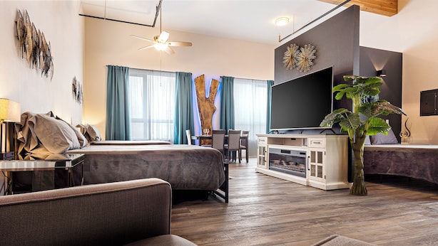 Ein modernes Hotelzimmer mit einem großen Bett, einer Couch, einem Fernseher und einem Kamin.