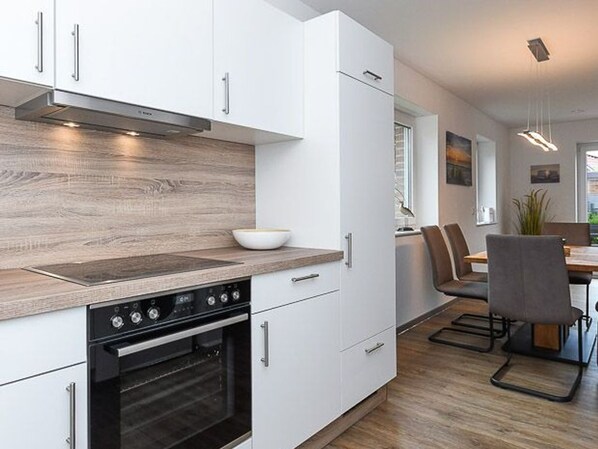 A modern kitchen with white cabinetry, a built-in oven, and a wooden countertop.