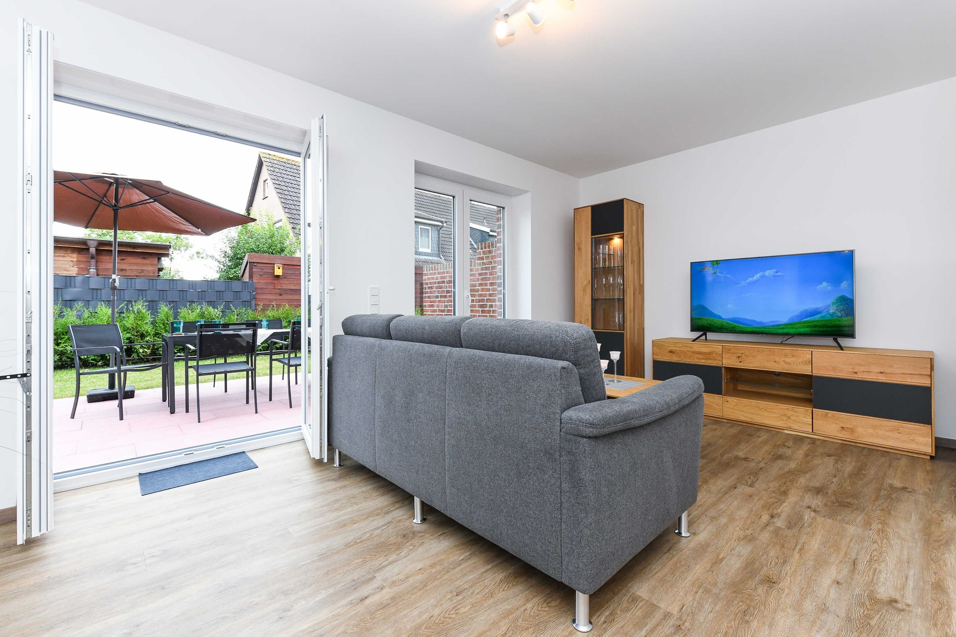 Un salon moderne avec un canapé gris, un meuble en bois et un téléviseur fixé au mur.