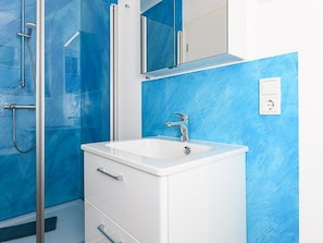 A bathroom with a white sink, a mirror above it, and a shower area with glass doors.