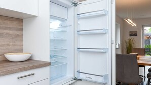 A modern kitchen with a built-in refrigerator, wooden countertop, and a dining area with a table and chairs.