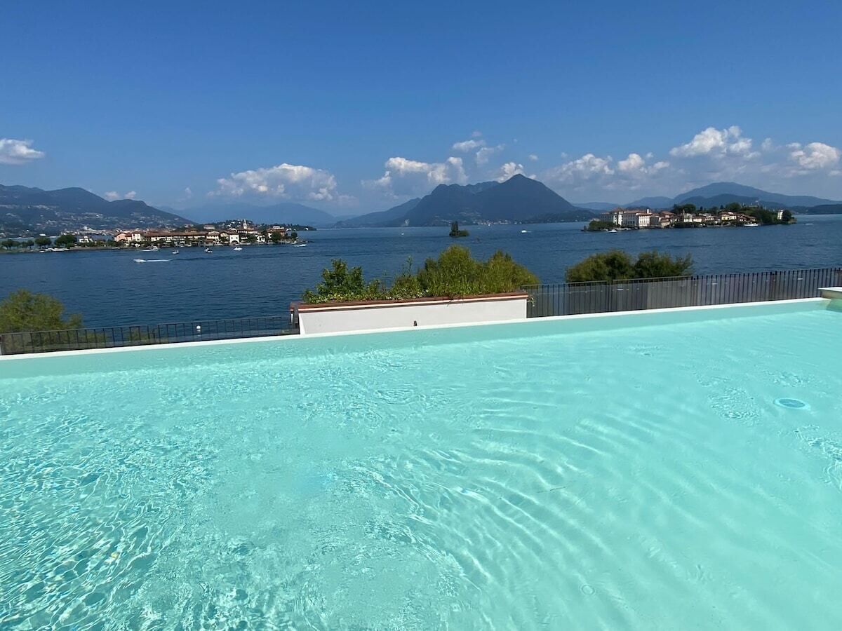 A clear swimming pool with a view of a lake and mountains in the background.