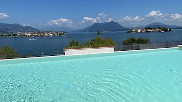 Una piscina trasparente con vista su un lago e montagne sullo sfondo.