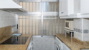 A modern kitchen with a built-in oven, microwave, and washing machine. - ESTRELLA, 2º-10 (Cullera)