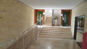 A hallway with a marble floor, a metal handrail, and a staircase leading to a door with a sign. - ESTRELLA, 2º-10 (Cullera)
