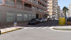 A multi-story residential building with balconies, a parking area, and a clear sky. - ESTRELLA, 2º-10 (Cullera)