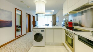 Una moderna camera d'albergo con lavatrice, angolo cottura e un'ampia finestra con tende.