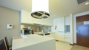 Una cucina moderna con mobili bianchi, un forno a microonde, una macchina per il caffè e un lavello.