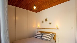 A bedroom with a bed, wooden ceiling, and wall-mounted lights.
