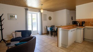 A compact living space with a kitchenette, a dining area, and a sofa with patterned cushions.