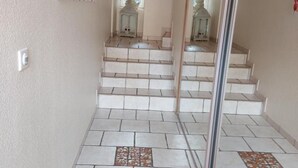 Un escalier recouvert de carreaux blancs, agrémenté de motifs décoratifs en mosaïque dans sa partie inférieure.