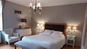 Une chambre bien rangée, avec un grand lit, des tables de chevet avec des lampes, une chaise et un banc.