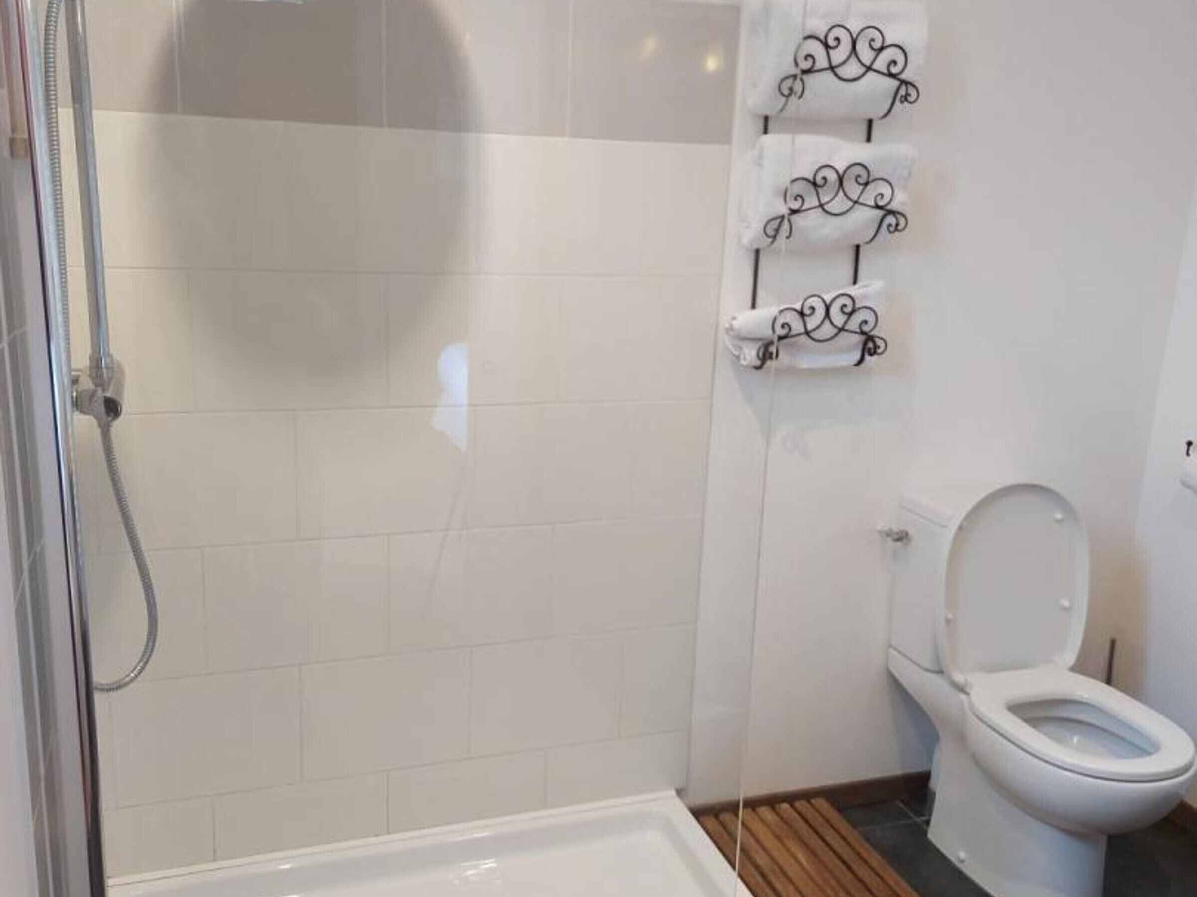 Ein Badezimmer mit Dusche, Toilette und Handtuchhalter.