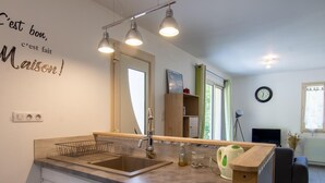 A modern kitchen with a dishwasher, a sink, and a wooden countertop. There is a mirror above the sink and a clock on the wall.