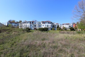 Una serie di edifici residenziali moderni a più piani con balconi, circondati da aree verdi e alberi.
