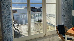 Una habitación con puerta de cristal corredera que da a un balcón con vistas a casas y un cielo nublado.
