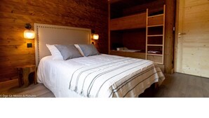 Una habitación de madera con una cama, una escalera y una puerta.