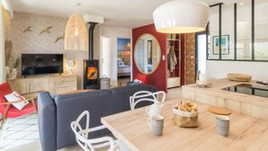 Een moderne woonkamer met een televisie, bank, eettafel en een open haard.
